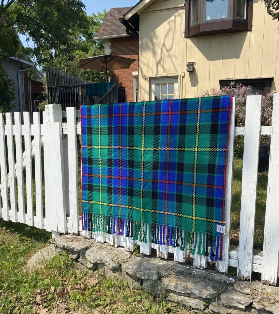 Liz Pead Tait Tartan draped on a white picket fence