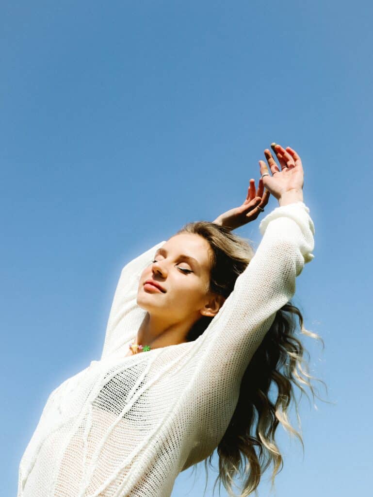 model posing expressively with eyes closed and arms above her head