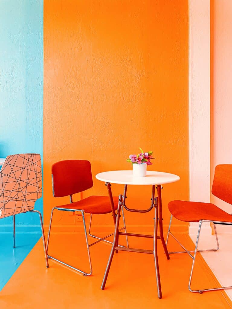 white table with dark orange chairs in an orange and aqua painted room